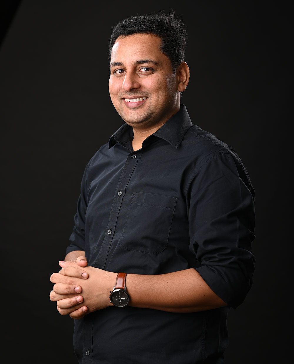 cheerful Coach Rajendra man in a black shirt, dark background, giving a strong and positive mindset vibe