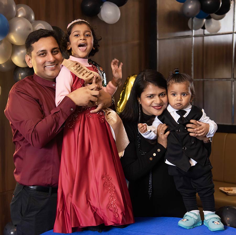 Coach Rajendra smiling with his family, laughing daughter and young boy and a proud confident women
