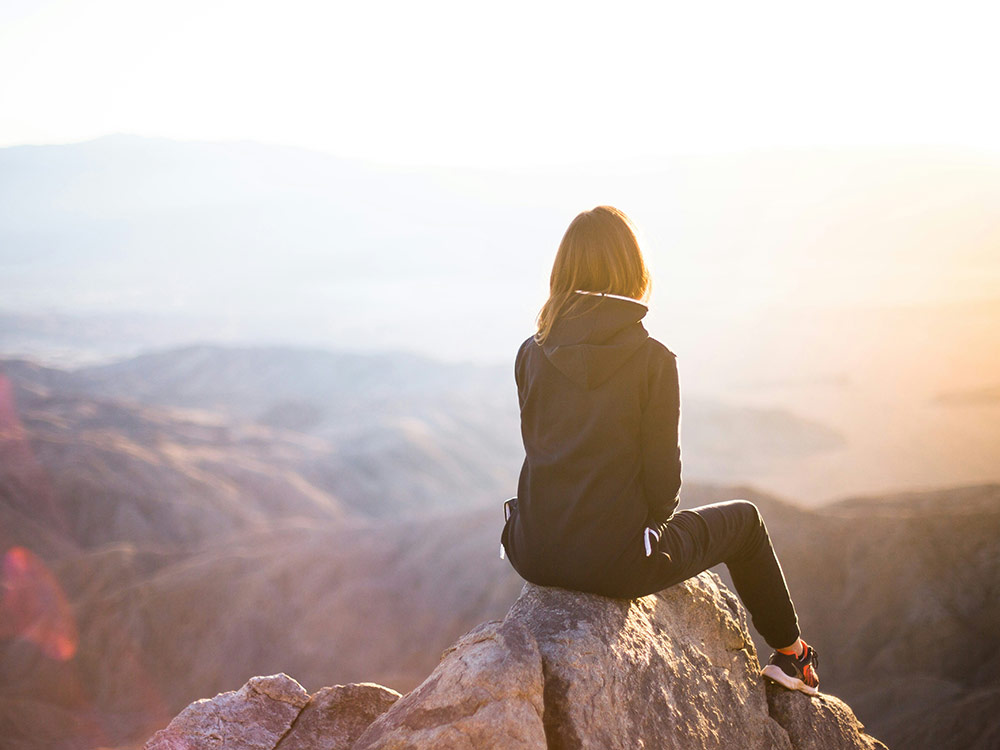 woman enjoys a sunset view from mountain signifying motivation and growth mindset 