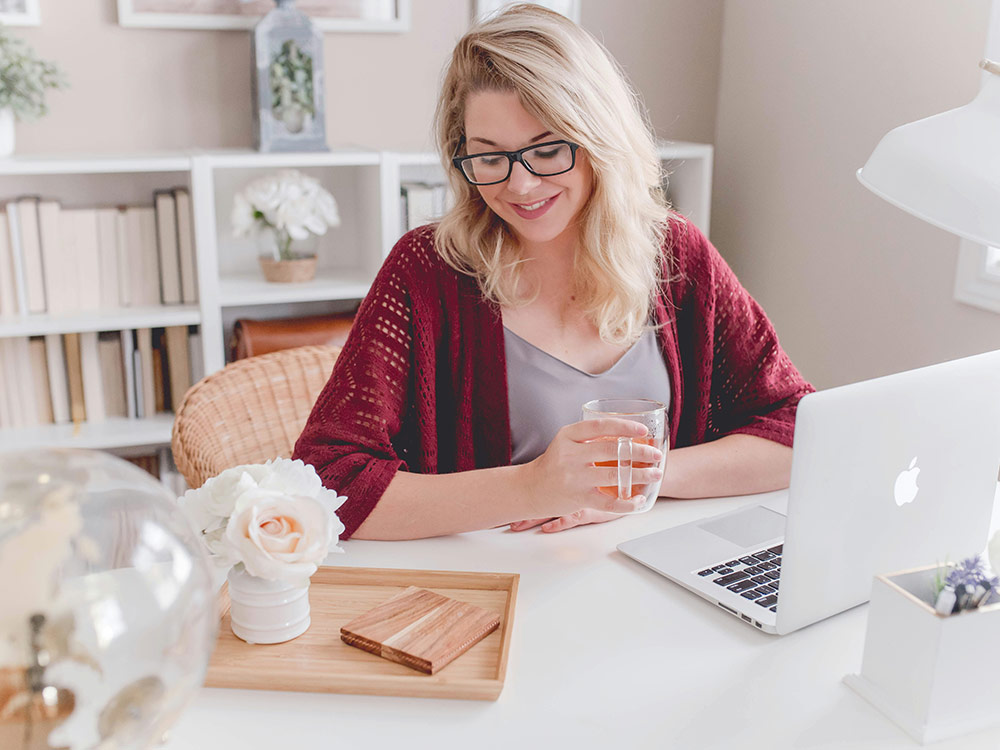 A calm faced woman in glasses sits at a desk, embodying the essence of work-life balance